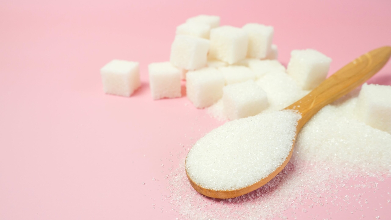 granulated-sugar-sugar-cubes-pink-background-with-space-text-min